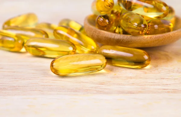 Closeup yellow soft gelatin supplement fish oil capsule on woode — Stock Photo, Image