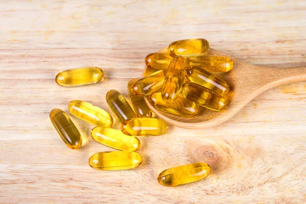 Closeup yellow soft gelatin supplement fish oil capsule on woode — Stock Photo, Image