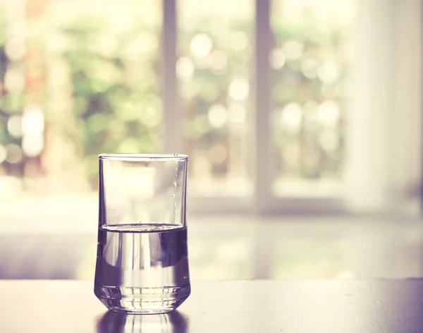 Closeup glas water op tafel in de woonkamer, vintage en retro stijl — Stockfoto