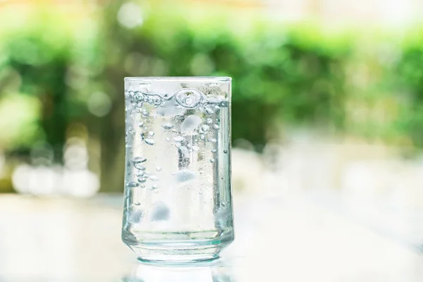Склянка прохолодного свіжого напою з кубиком льоду і бульбашкою на столі — стокове фото