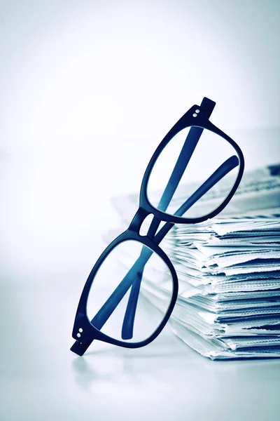 Reading eyeglasses with stacking of newspaper background , busin — Stock Photo, Image