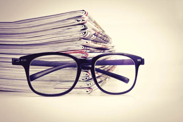 Selective focus on reading eyeglasses with stacking of newspaper — Stock Photo, Image