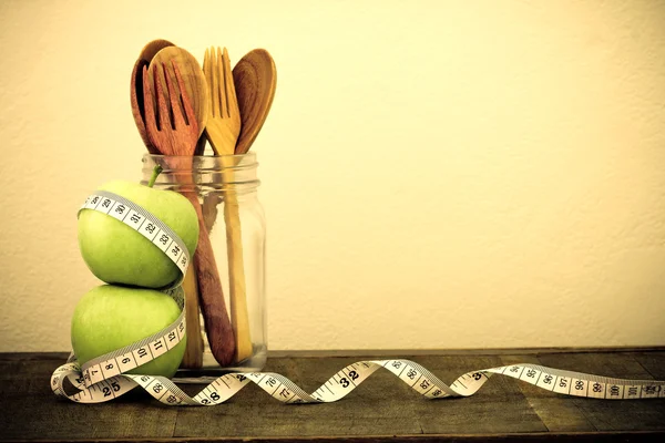 Green apple with Measuring tape and wooden spoon and fork on woo — Stock Photo, Image