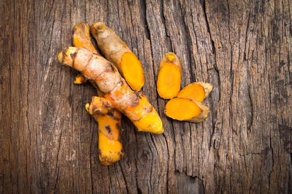 Raíz de cúrcuma en placa de madera — Foto de Stock