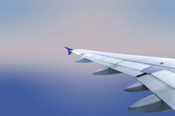 Wing of an airplane flying above the clouds — Stock Photo, Image