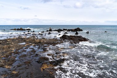 İspanya 'nın Lanzarote kentindeki Punta Mujeres' in engebeli kıyı şeridi okyanusun kıyılarla buluştuğu volkanik kaya oluşumlarını gösteriyor..