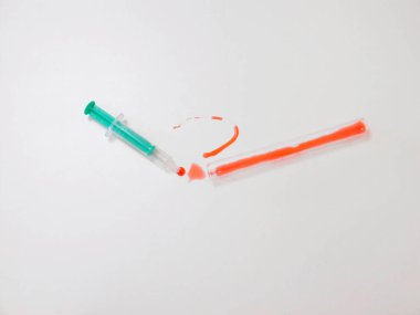 Beyaz yüzeyde yeşil şırınga ve kan lekesi, tıbbi atık ve kirlilik riski,