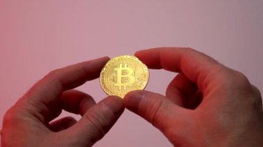 Mans el kırmızı ışıkta altın bir bitcoin gösteriyor.