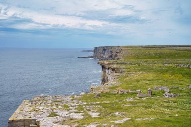Dramatik sahil kayalıkları İrlanda 'da bulutlu bir gökyüzünün altında okyanusla buluşuyor..