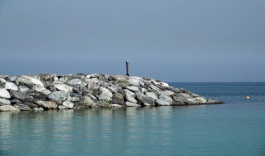 Sahili deniz dalgalarından korumak için dev taşlardan oluşan bir setten gelen dalgalı su.