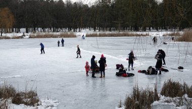 Kiev, Ukrayna 6 Şubat 2021: Yetişkinler ve çocuklar donmuş bir gölün buzuna biniyorlar