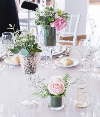 Dekorasyon olarak pembe güller ve yeşil yapraklarla dolu bir düğün masasının ayrıntıları.