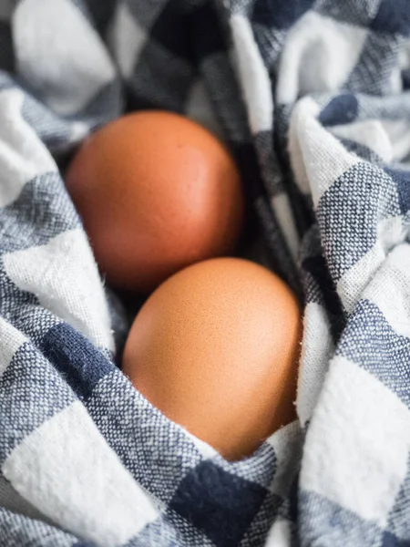 Two beige chicken eggs lie on a checkered mat. Healthy food vertical background. Easter concept. Close-up