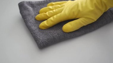 Temizlik ve dezenfeksiyon konsepti. Sarı lastik eldivenli el, Coronavirus COVID-19 'un yayılmasını önlemek için gri antibakteriyel dezenfektan peçeteyle masayı temizler. Moda Renkleri 2021