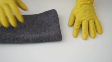 Temizlik ve dezenfeksiyon konsepti. Sarı lastik eldivenli el, Coronavirus COVID-19 'un yayılmasını önlemek için gri antibakteriyel dezenfektan peçeteyle masayı temizler. Moda Renkleri 2021