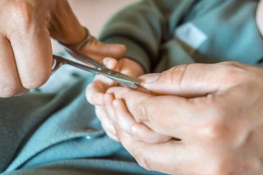 Annem yeni doğmuş bebek tırnaklarını makasla kesiyor. Yeni doğmuş bir bebeğin elleri ve elleri yakındır. Çocuk manikürü