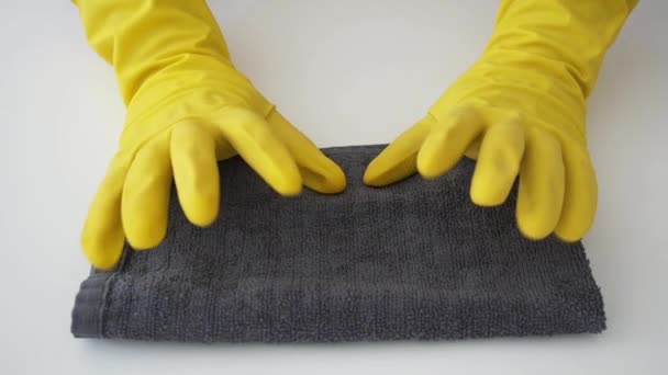 Conceito de limpeza e desinfecção. Mãos de close-up em luvas de borracha amarela batendo no toalhete desinfetante antibacteriano cinza para evitar a propagação do coronavírus COVID-19. Cores da moda 2021 — Vídeo de Stock