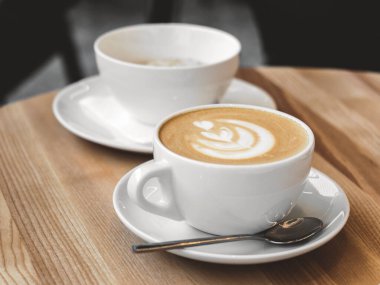 Tahta masada sütlü bir fincan kahve. Kahve dükkanında sütlü sıcak kapuçino ya da latte. Kafede sabah kahvaltısı. Yaşam biçimi