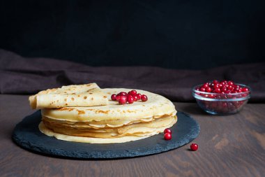 Yığınla ya da ev yapımı Rus ev yapımı krep ya da yuvarlak taş tepside koyu kahverengi ahşap masada tekstil ile yenmeye hazır kırmızı çilekli krep. Kopyalama alanı olan resim, yatay