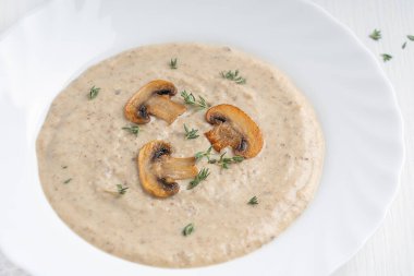 Kremalı mantar çorbası püresinin yakından görüntüsü harmanlanmış şampiyonlar, patates ve süt kreması kızartılmış dilimler ve kekik ile süslenmiş ve öğle yemeğinde ahşap masada servis edilen kekik. Yatay