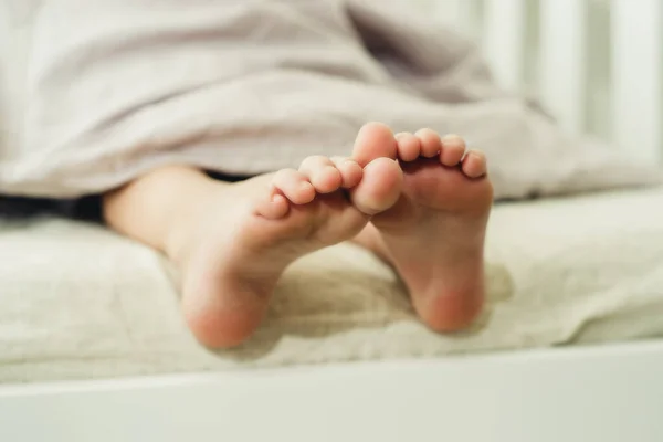 baby little feet under a light blanket close-up