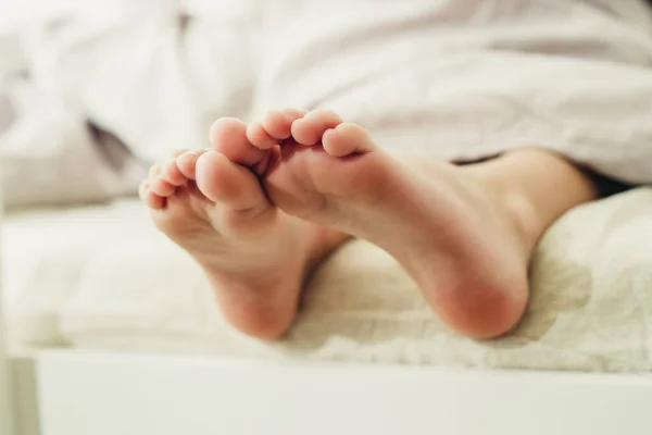 baby little feet under a light blanket close-up