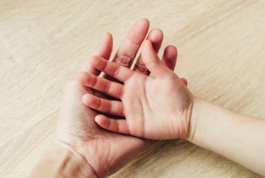 Çocukların elleri yetişkinlerin elinde, yakın plan.