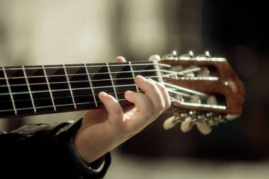 Gitar çalan çocuk ellerin yakın çekimini yapıyor