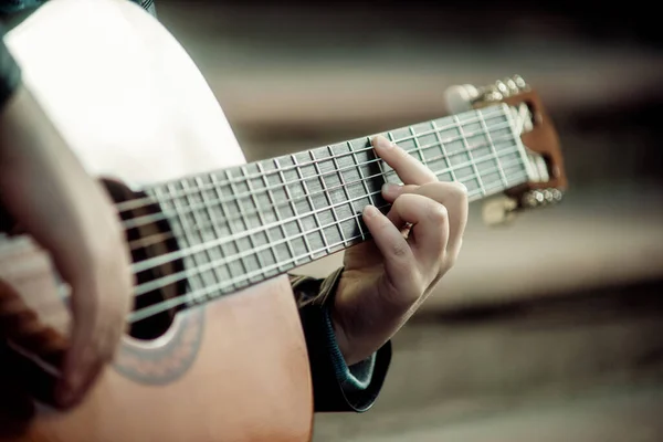 Gitar çalan çocuk ellerin yakın çekimini yapıyor