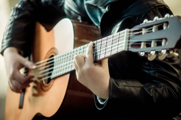 Gitar çalan çocuk ellerin yakın çekimini yapıyor