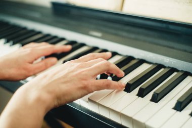 Eller piyano tuşlarında, yakın plan.