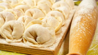 Kesme tahtasında Rus köftesi. Hamur köftelerini pişirme yöntemi. Etli Rus böreği. Ev yapımı ravioli. fotoğraf