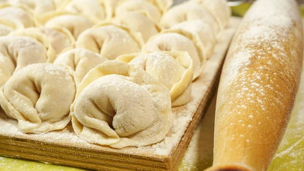 Kesme tahtasında Rus köftesi. Hamur köftelerini pişirme yöntemi. Etli Rus böreği. Ev yapımı ravioli. fotoğraf