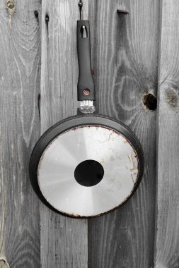 Eski bir tava. Kızartma tavası tahta bir tahtanın üzerinde asılı..