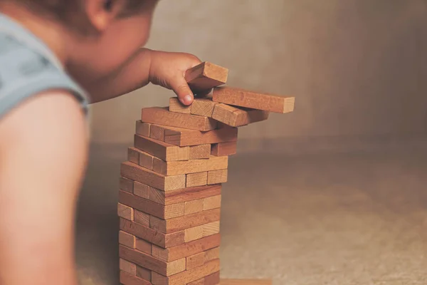 The child\'s hands pushed the brick and destroyed the tower. Janga wooden box. An imbalance. destruction of blocks. Mistake. Entertainment activities. A game of physical and mental skill.