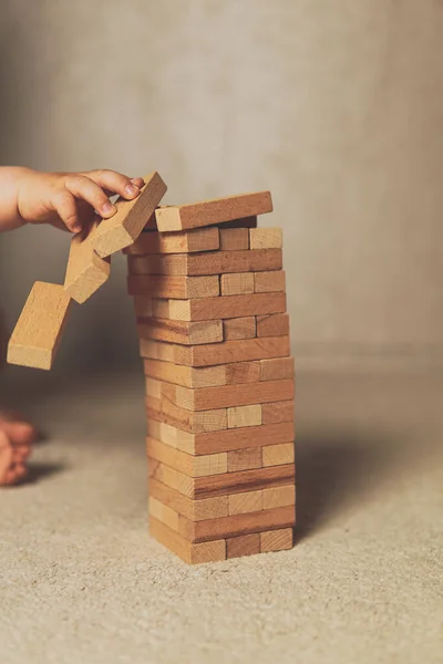 The child's hands pushed the brick and destroyed the tower. Janga wooden box. An imbalance. destruction of blocks. Mistake. Entertainment activities. A game of physical and mental skill.