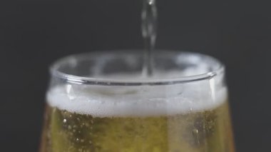 Hafif soğuk bira bardağa dökülüyor. Kapatın. Siyah arkaplanda izole