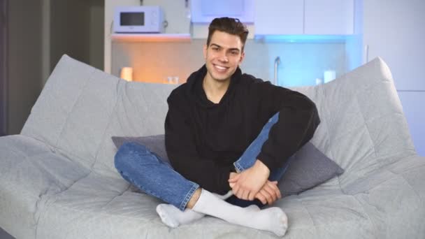 거실 소파에 앉아 미소짓는 젊은 청년의 모습 — 비디오