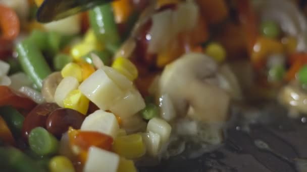 Homme cuisson mélanger les légumes dans une poêle sur une cuisinière électrique, au ralenti — Video