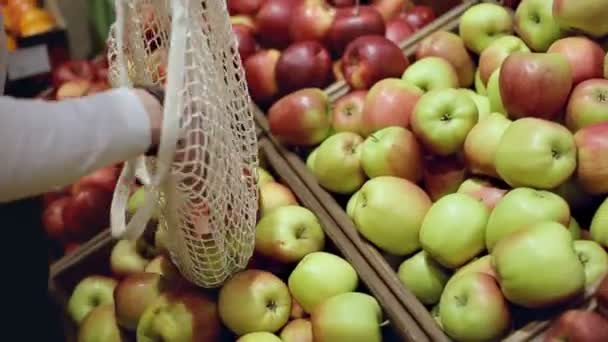 İnsan eli kapalı markette elmaları eko torbaya koyar. — Stok video