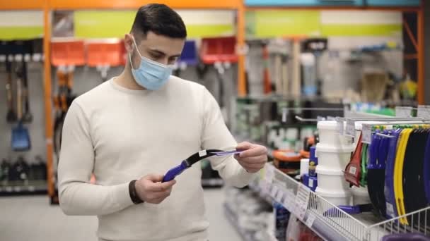 Hombre con máscara elige rascadores de coches para limpiar el coche en la tienda. — Vídeos de Stock