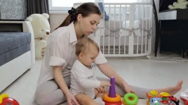 Genç bir kadın yerde oyuncaklarıyla oynuyor.