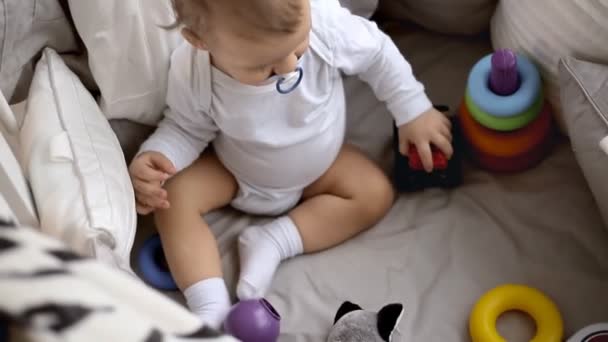 Niedliche Baby Junge spielt mit Auto Spielzeug sitzen im Bett. — Stockvideo