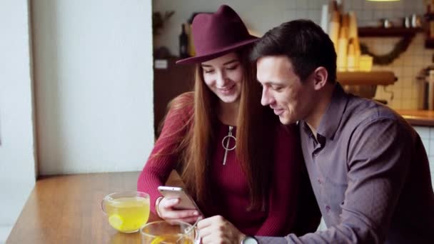 Jeune couple utilisant smartphone ensemble et boire du thé dans le café loft — Video