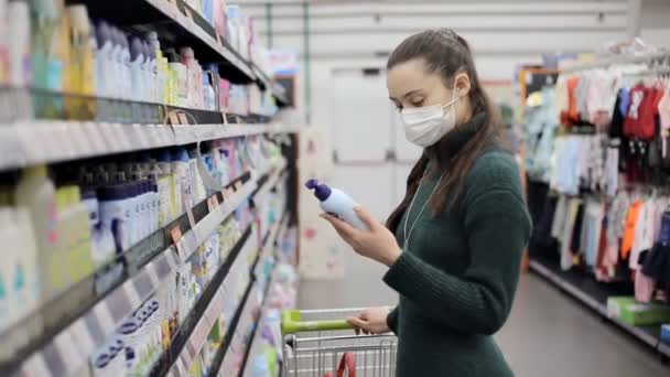 Mujer cliente con máscara médica elegir gel de ducha o champú en el supermercado — Vídeos de Stock