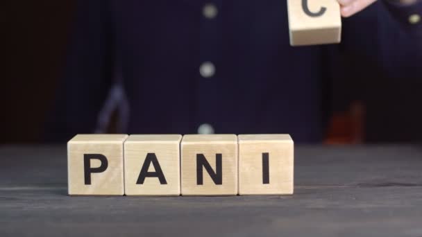 Un hombre con camisa compone la palabra PANIC de cubos de madera, de cerca — Vídeos de Stock