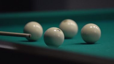 Bir adam beyaz topa ıstakayla vuruyor. Yeşil masada bilardo oynuyorum..