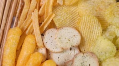 Birçok çeşit sağlıksız tuzlu abur cubur: cips, kraker, kraker, soğan halkaları. Üst Manzara. Çevirme videosu