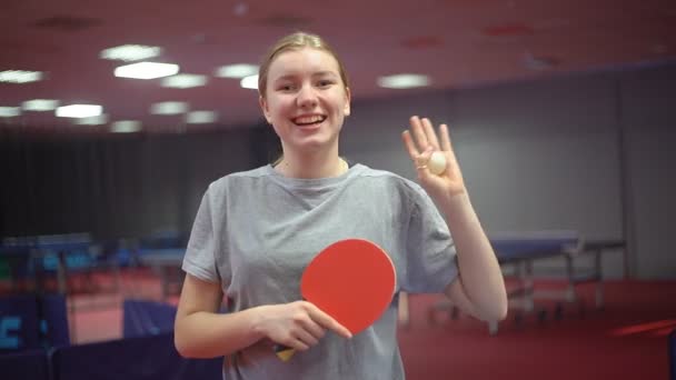 10 대 여자 테니스 선수가 탁구 라켓을 들고 웃는 모습. 손흔들기 — 비디오