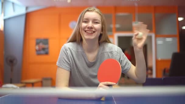 Portrait d'une adolescente souriante joueuse de tennis de table avec une raquette de ping pong. Agitant la main — Video